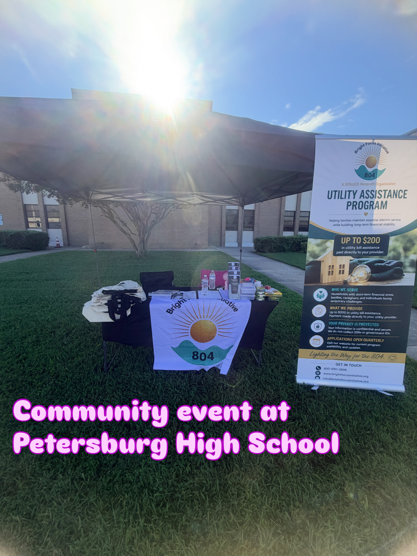 Bright Focus Initiative 804 booth with utility assistance banner on the lawn at Petersburg High School
