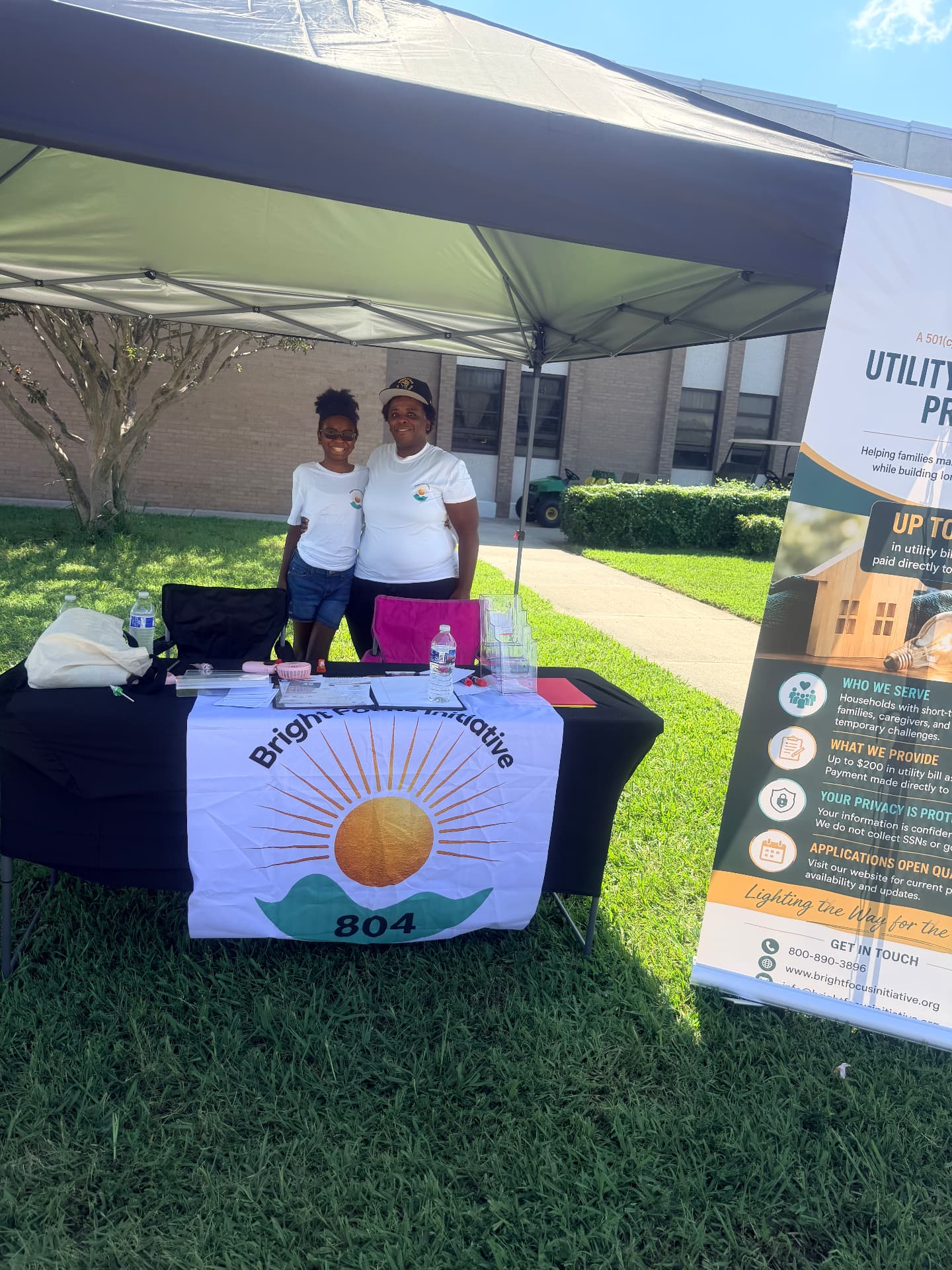 Two volunteers smiling behind the Bright Focus Initiative 804 table